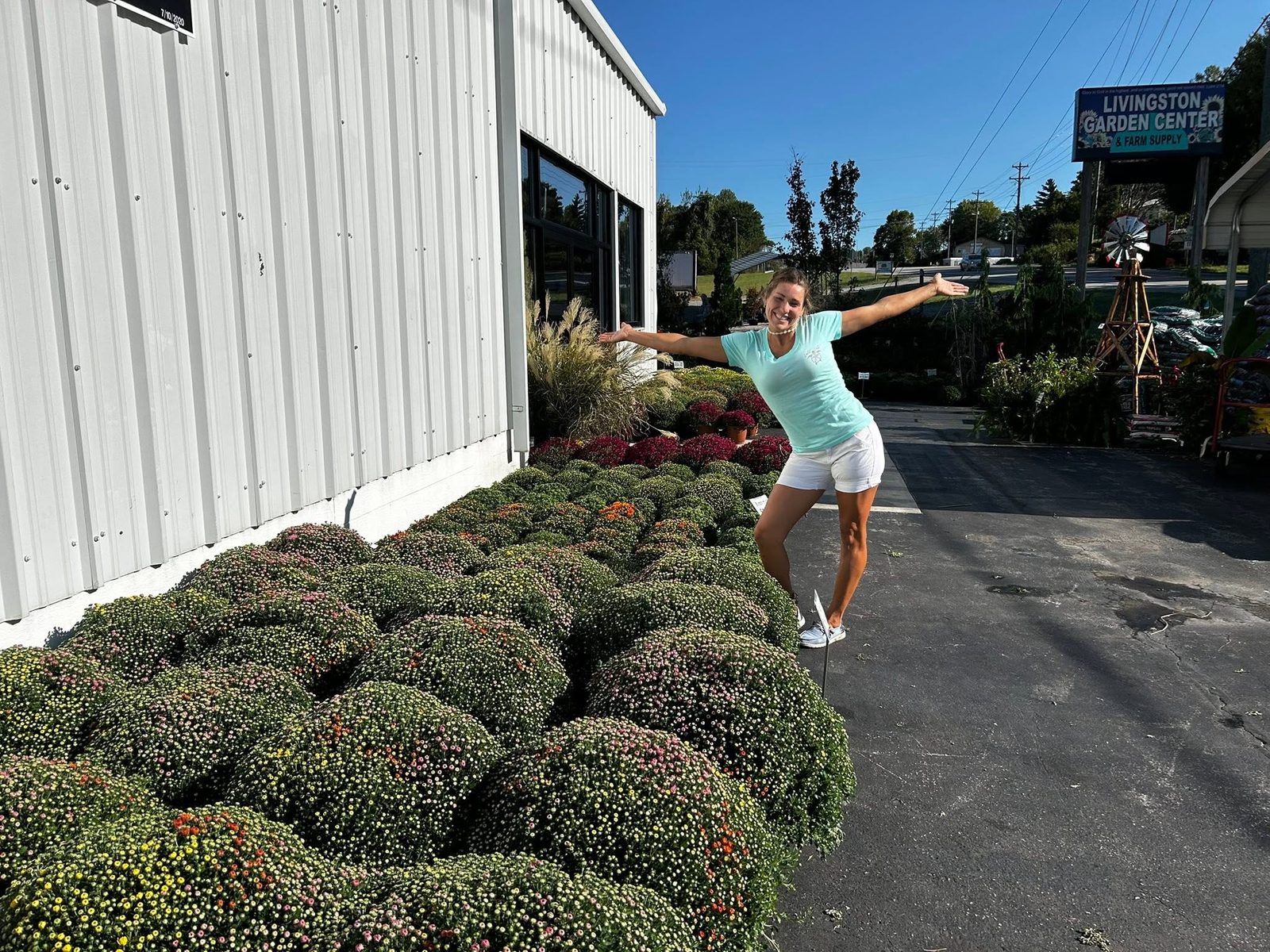 Elisa out front with the fall mum benches under the road sign