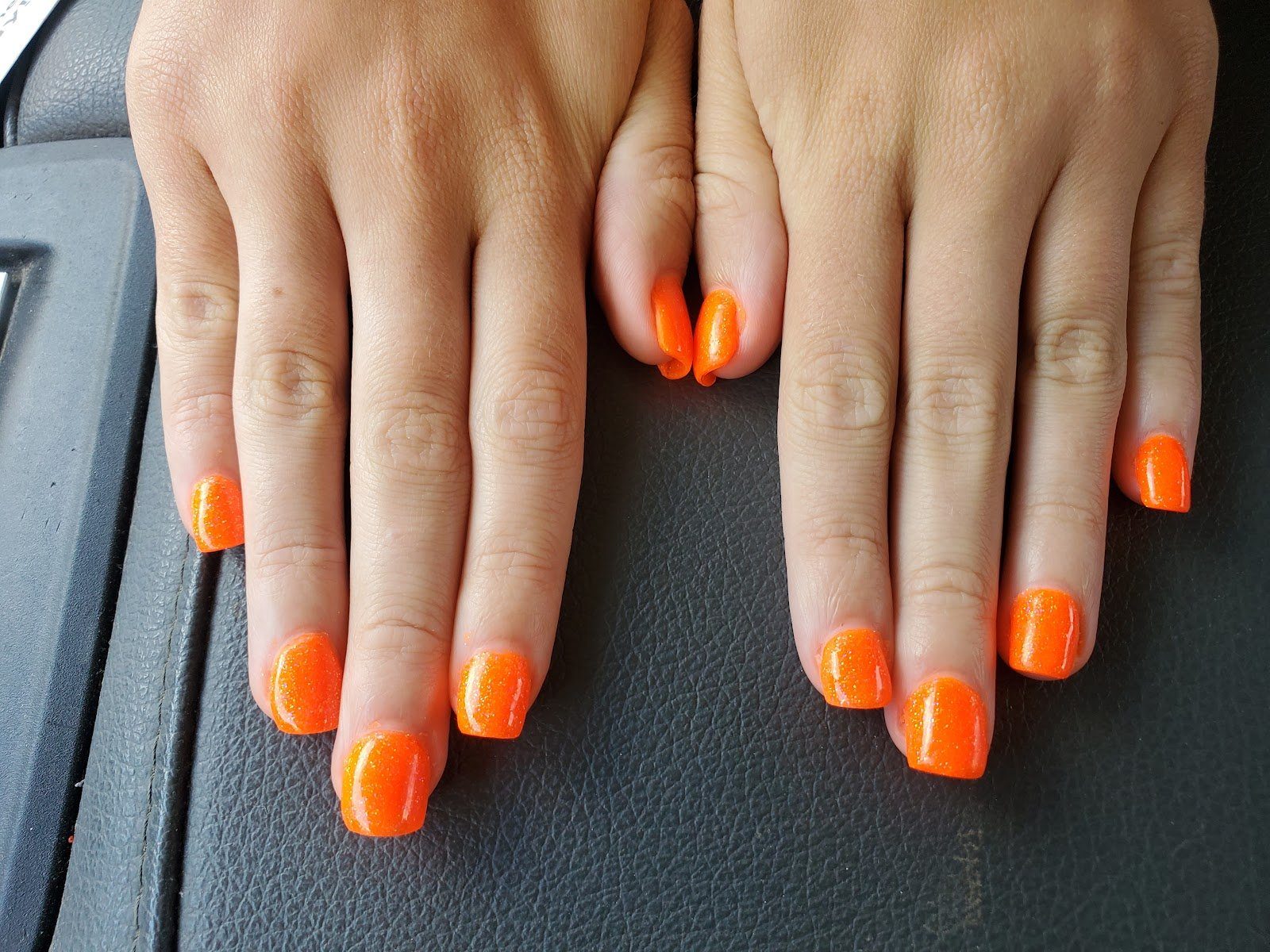 A manicure done in orange nail polish at Pamie's Unisex Hair Salon