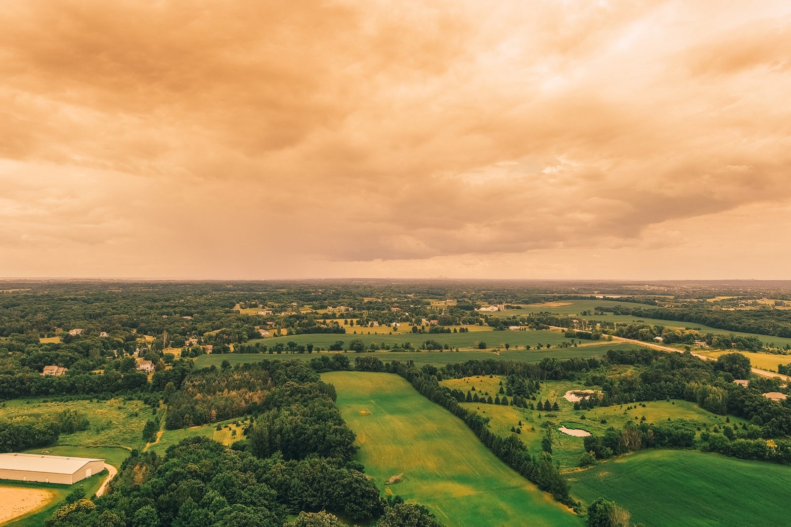 Twilight aerial over fields under an amber sky