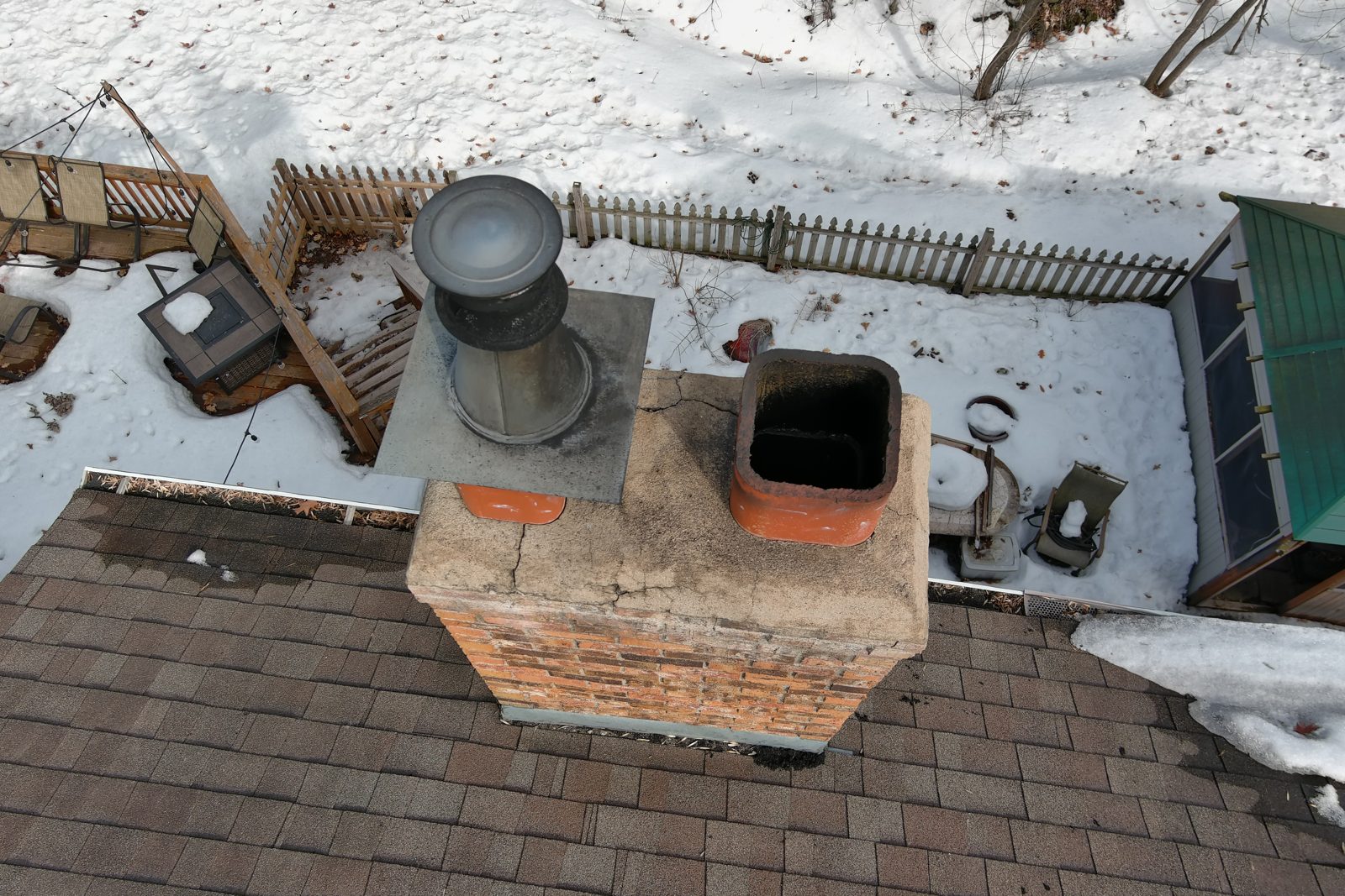 Close-up drone inspection of a brick chimney and shingle roof